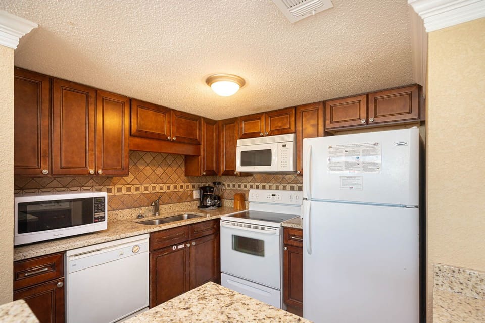The kitchen features rich wooden cabinetry, granite countertops, and essential appliances for a delightful cooking experience
