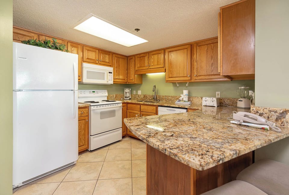 Prepare meals in this kitchen with ample counter space, wooden cabinetry, and white appliances