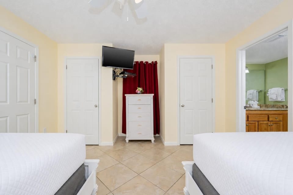 Cozy guest bedroom featuring two double beds, a TV, and easy access to the adjoining bathroom