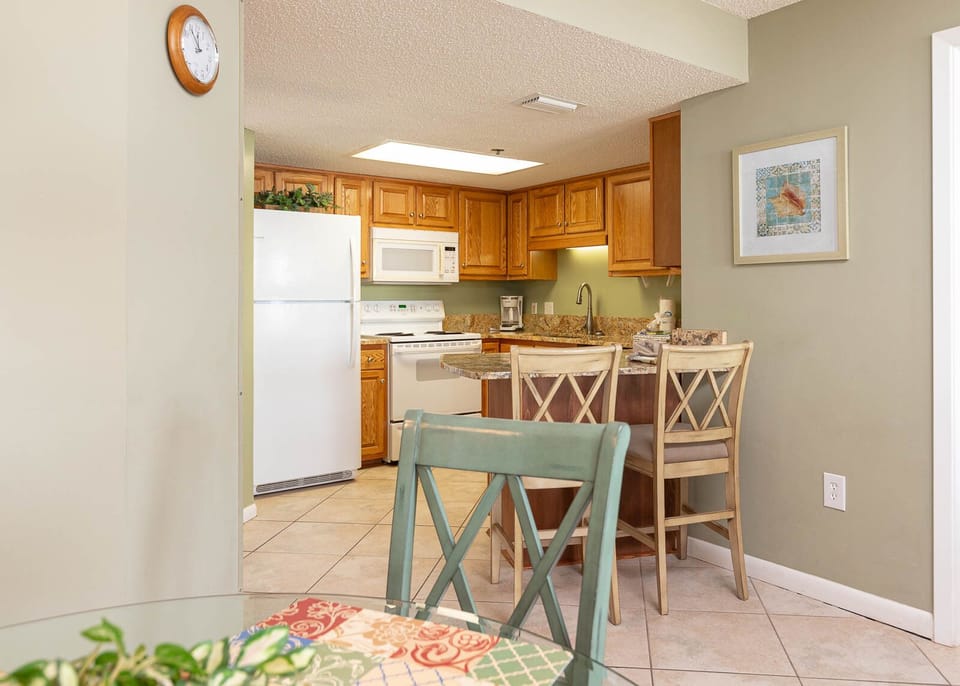 Cook and dine in the inviting kitchen area featuring warm wood cabinetry and a cozy breakfast bar for shared meals