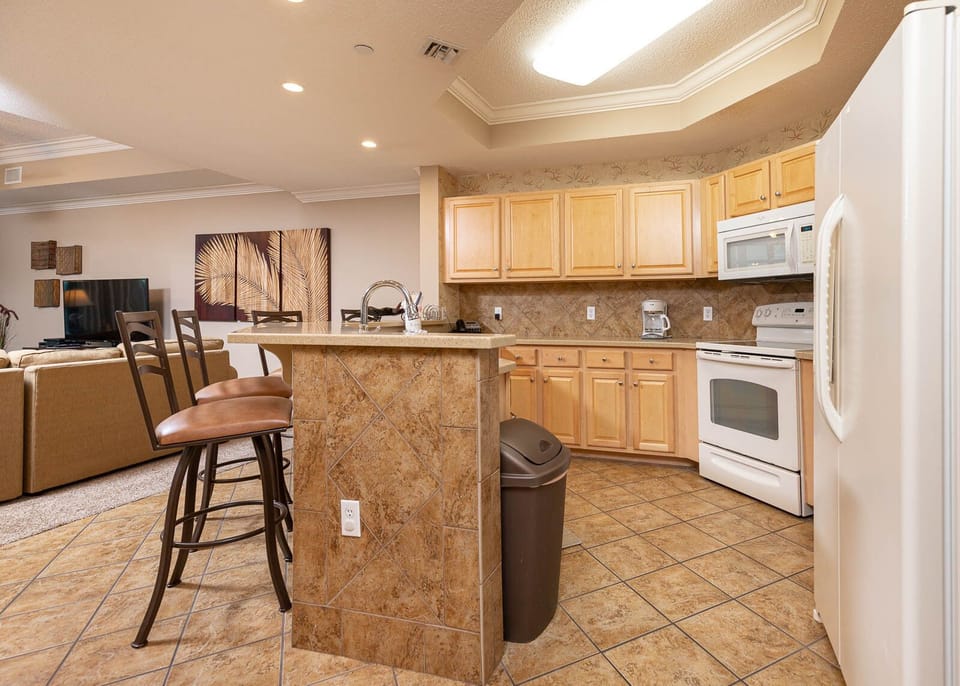 Prepare meals in this kitchen with elegant cabinetry, white appliances, and spacious countertops