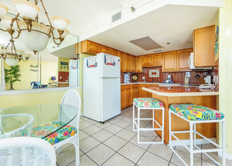 The kitchen features warm wooden cabinetry, a colorful tiled backsplash, and a convenient layout for meal preparation