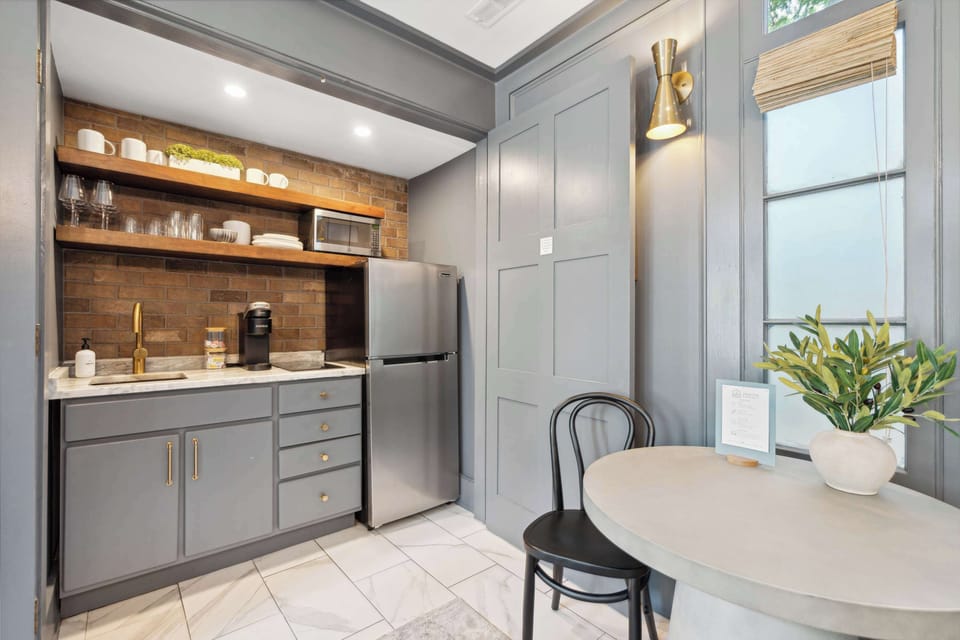 The stylish kitchenette features a fridge, microwave, induction cooktop, toaster oven, coffee maker, and open shelving for easy access to essentials. 