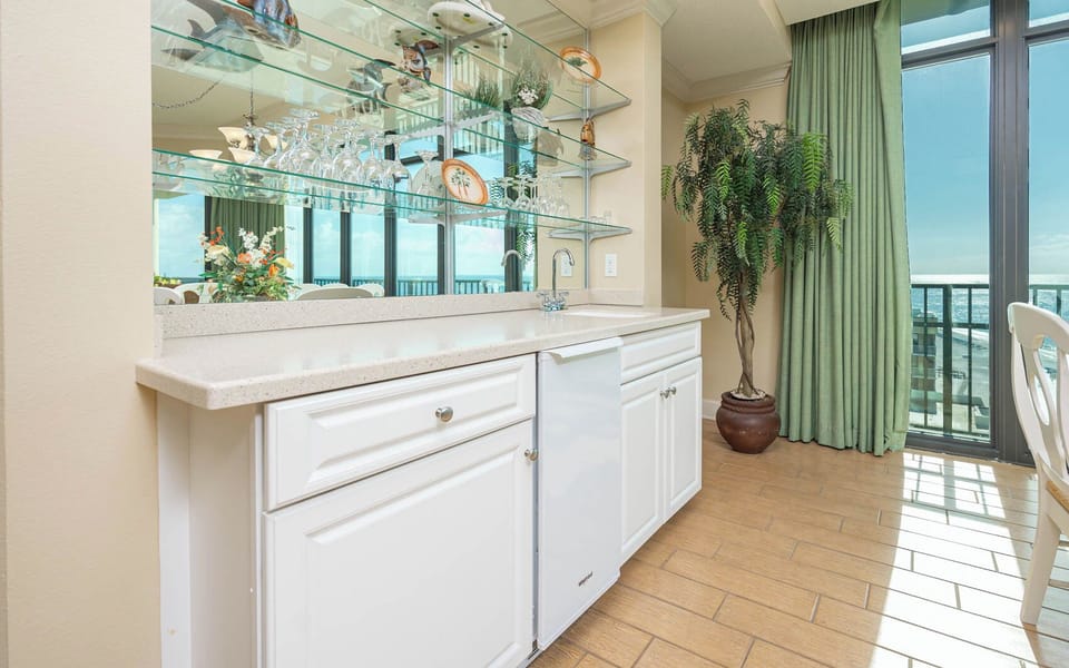 Create your favorite cocktail at the wet bar with elegant glassware displays with coastal accents