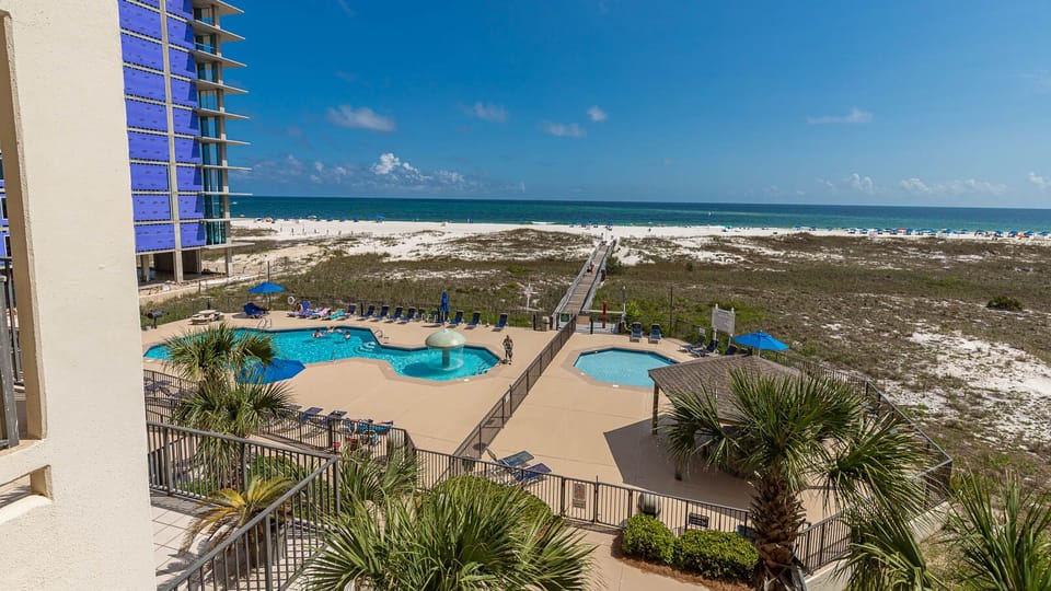 Stunning vew of the pool area featuring a fun mushroom water fountain, with the beach and Gulf visible in the background