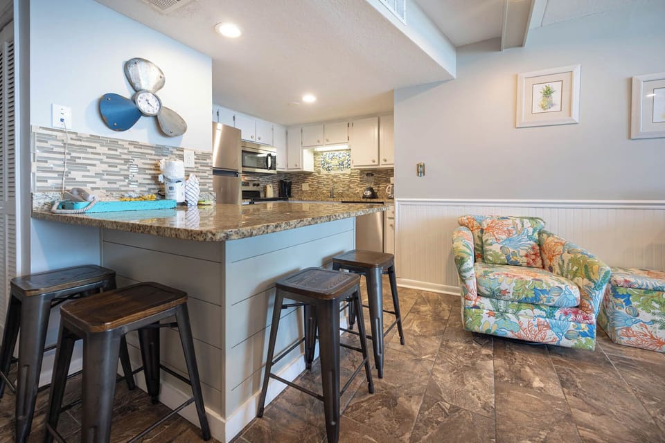 The kitchen features stylish cabinetry, stainless appliances, and a bar stool area perfect for relaxing