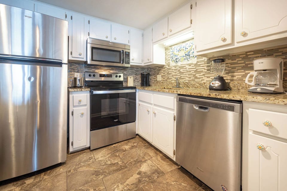 This kitchen features stainless appliances, granite countertops, and a stylish backsplash, perfect for meal preparation