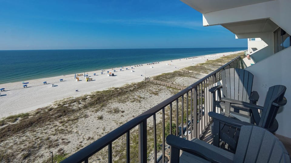Enjoy breathtaking beachfront views from this balcony, featuring comfortable seating for relaxation and unwinding