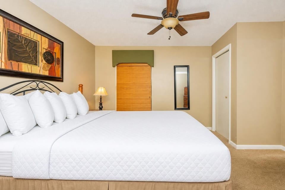 The master bedroom features a plush king bed, a stylish ceiling fan, and warm accent decor for a restful retreat