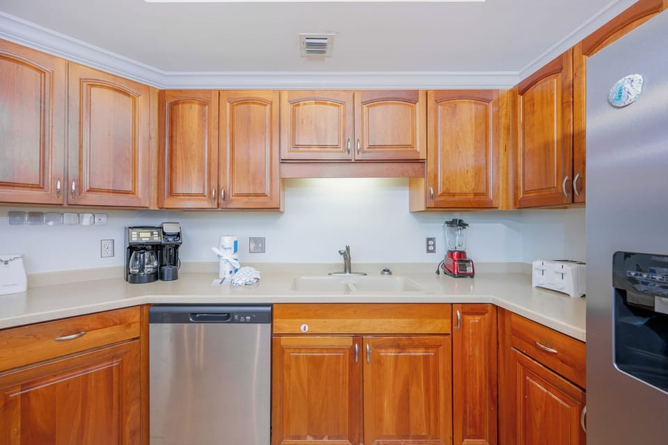 Prepare meals in this kitchen with wooden cabinetry, stainless appliances, and spacious countertops