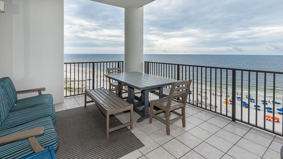 This sixth-floor balcony features a dining table and chairs, perfect for enjoying meals with a beachfront view