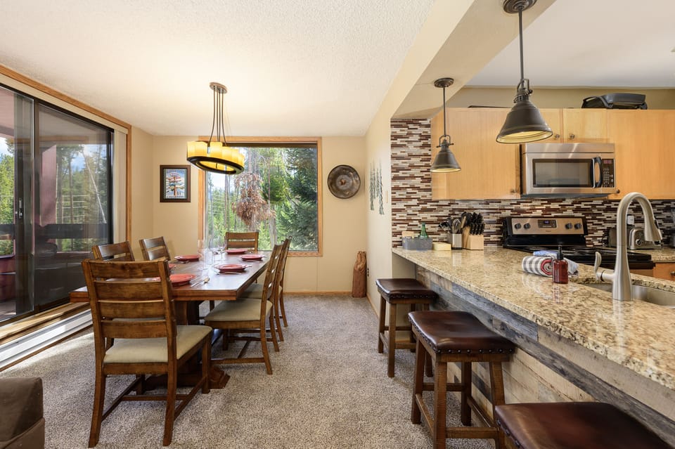 A modern dining and kitchen area with a breakfast bar and large dining table, enough seating for the whole crew