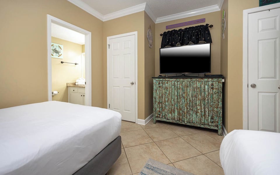 Relax in a cozy guest bedroom featuring two double beds, a flat-screen TV, and charming decor for a restful stay