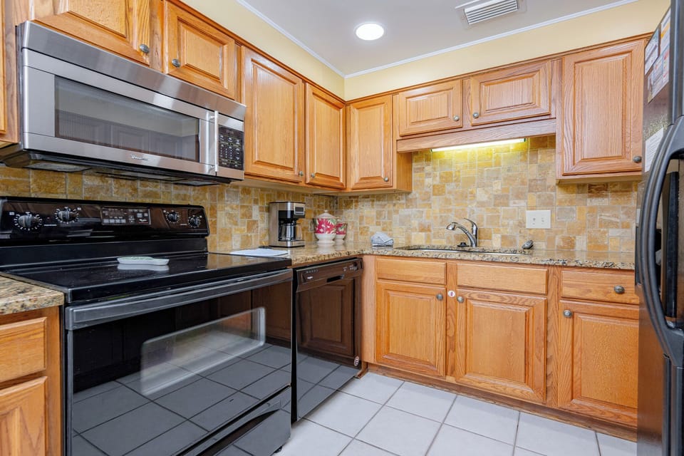 This kitchen features modern appliances, granite countertops, and a coffee maker, perfect for your culinary adventures