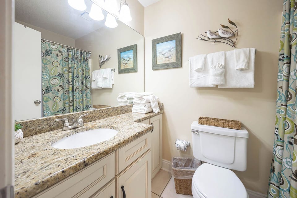 Refresh in this guest bathroom featuring a granite countertop, decorative art, and soft towels for your comfort