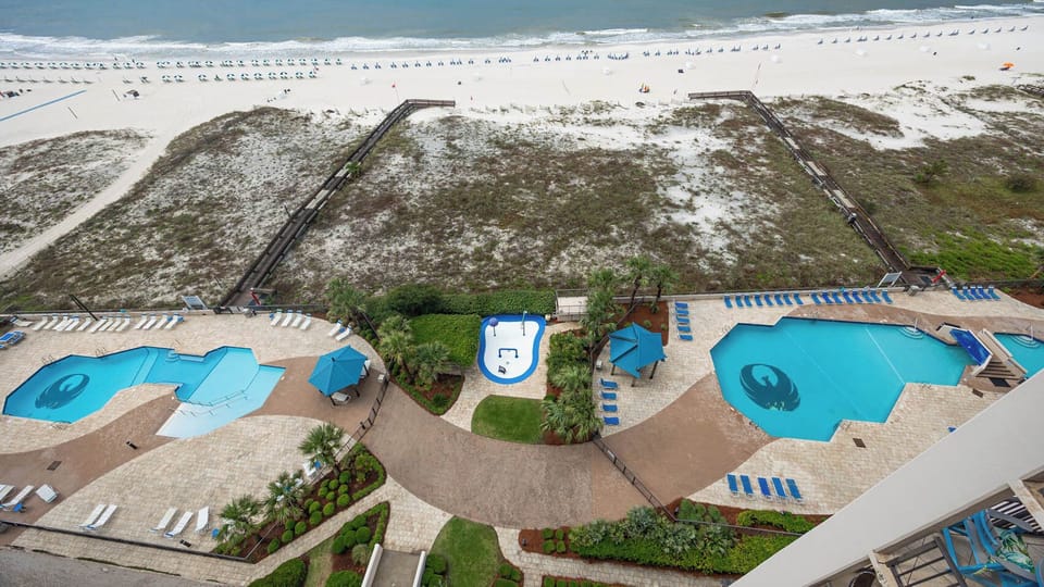 Relax by the inviting pools surrounded by lush landscaping, with easy access to the beach just steps away
