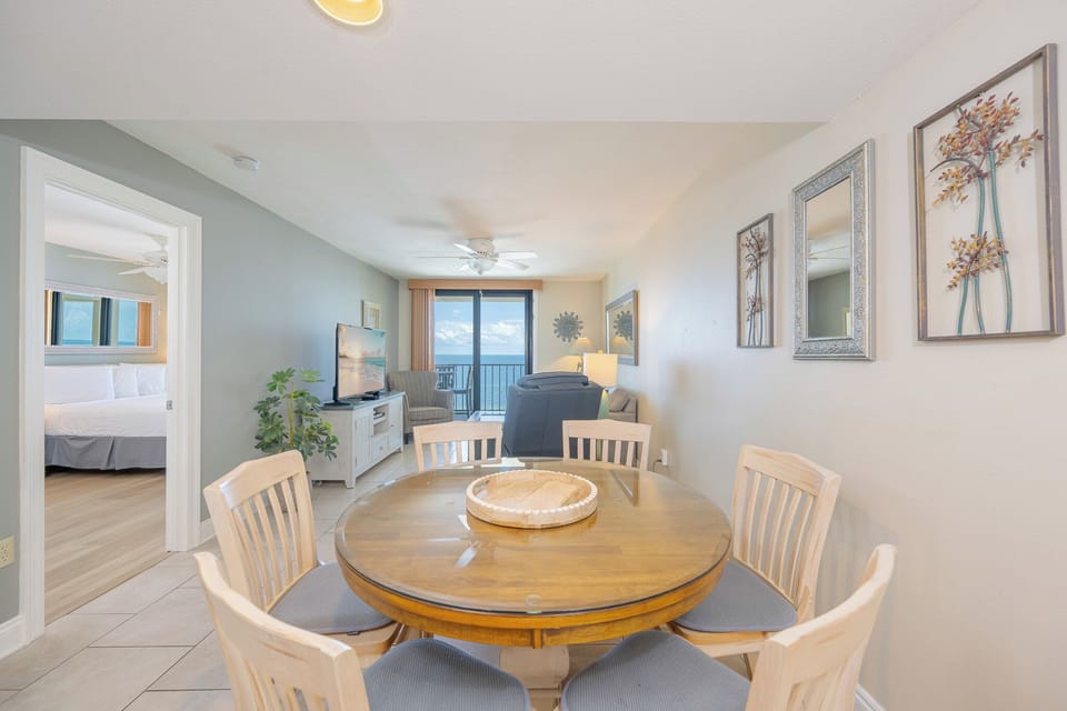 Inviting living space featuring a glass dining table, cozy seating, and a breathtaking view of the coastline