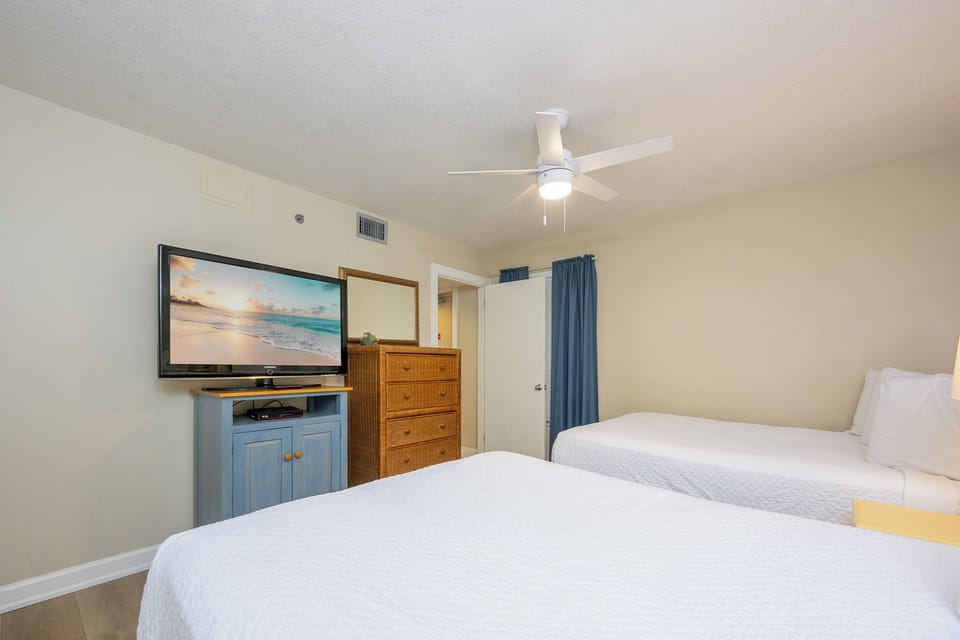 Cozy guest bedroom featuring two double beds, a large TV, and warm, inviting decor for a relaxing stay