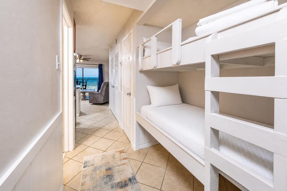 This cozy alcove features a built-in bunk bed, perfect for kids, with a view of the inviting living area and beach front