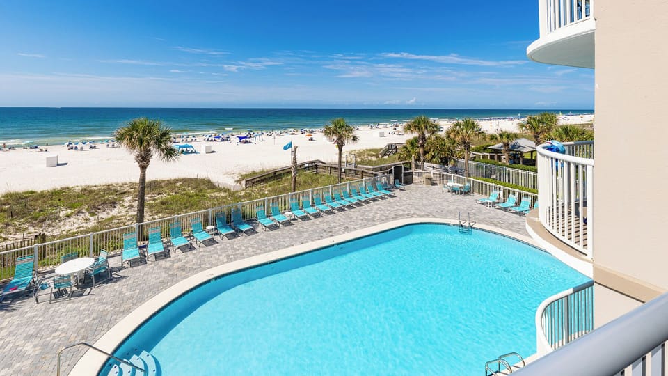 This inviting view showcases a sparkling pool surrounded by lounge chairs, with a stunning beach just steps away