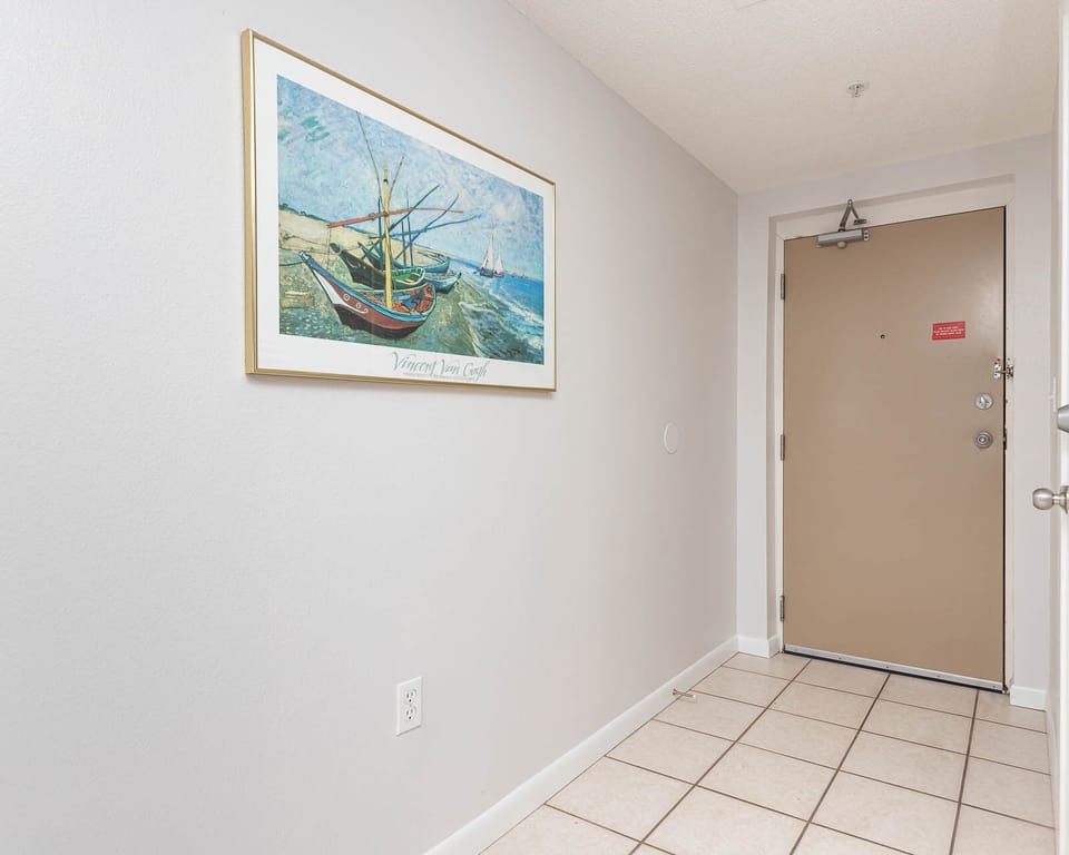 Step into a welcoming entryway adorned with coastal artwork and tiled flooring, setting a relaxed tone for your stay
