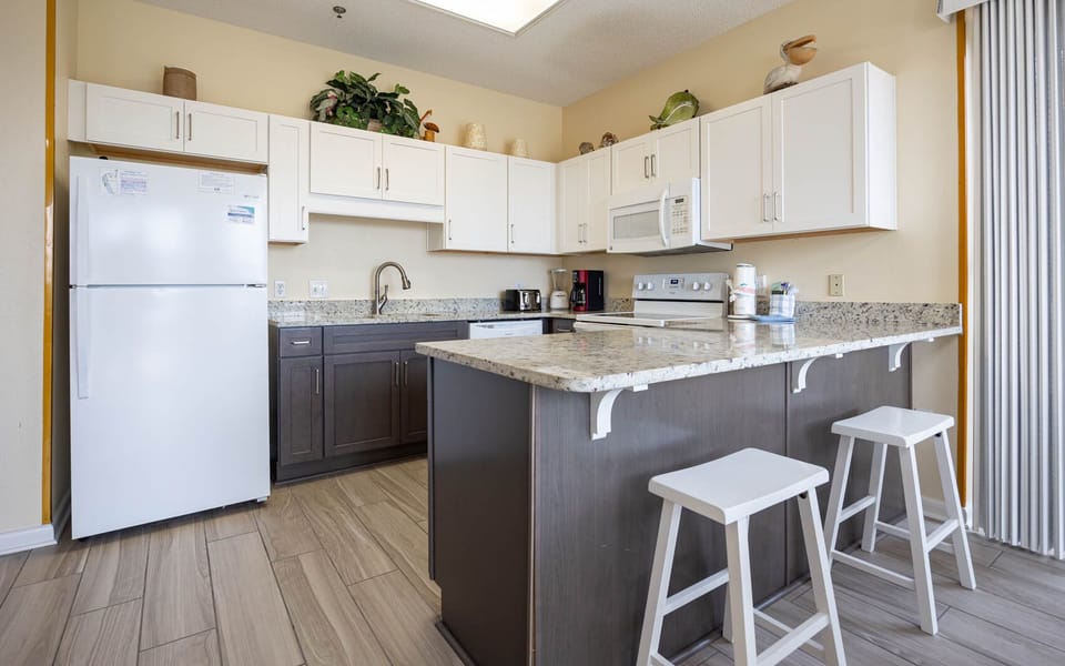 Prepare meals in this inviting kitchen with granite counters, white appliances, and seating for casual dining