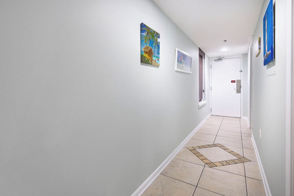 Step into a welcoming hallway adorned with vibrant artwork and stylish tile flooring, leading to your vacation retreat