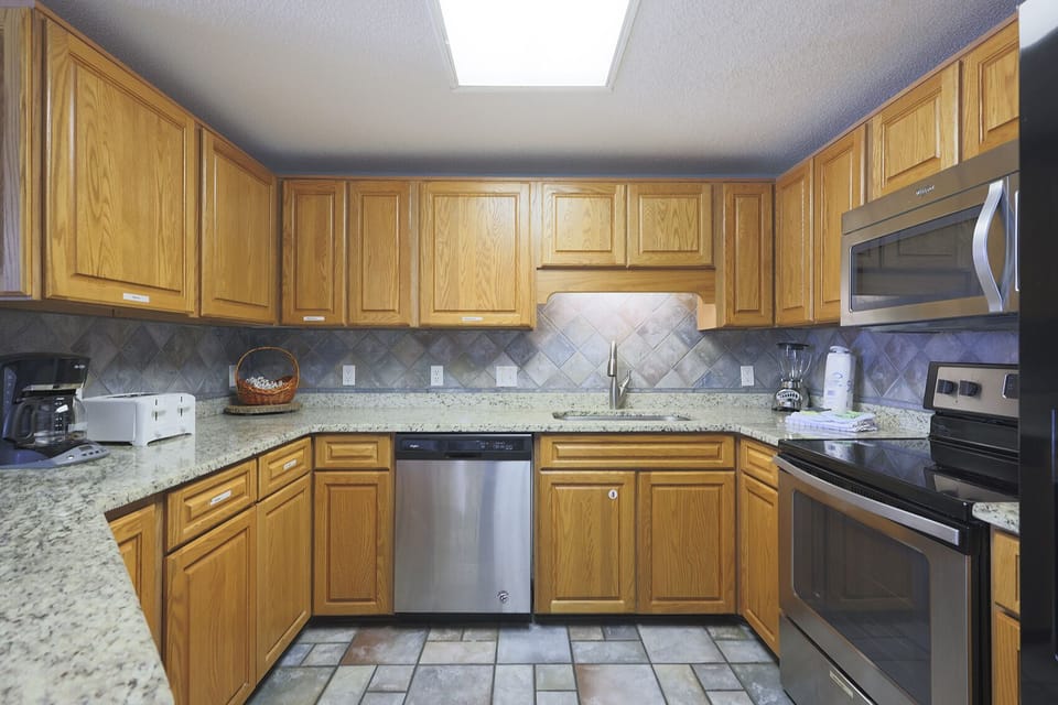 Warm wooden cabinetry complements the spacious counter, featuring stainless appliances, and a coffee maker