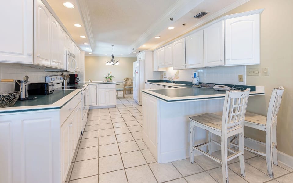 Open and spacious kitchen design, featuring white cabintery and appliances, and additional counter space