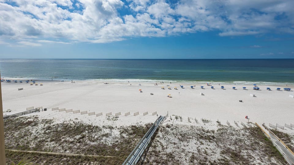 Enjoy a serene view of the beach front with white sand and colorful umbrellas, perfect for relaxing under the sun