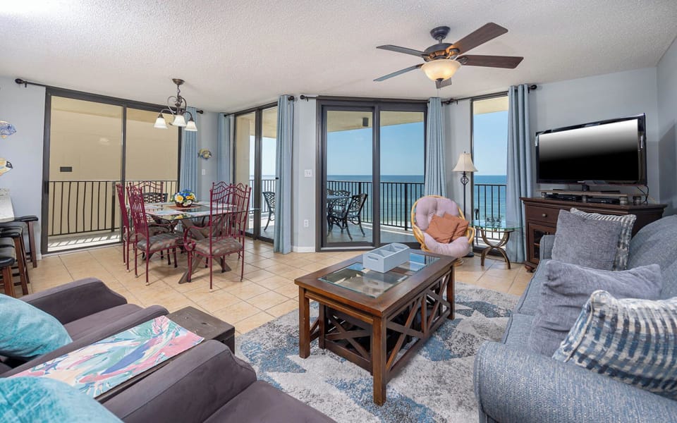Living area featuring a cozy sofawith queen sleeper, dining table, and expansive views of the beach through large windows