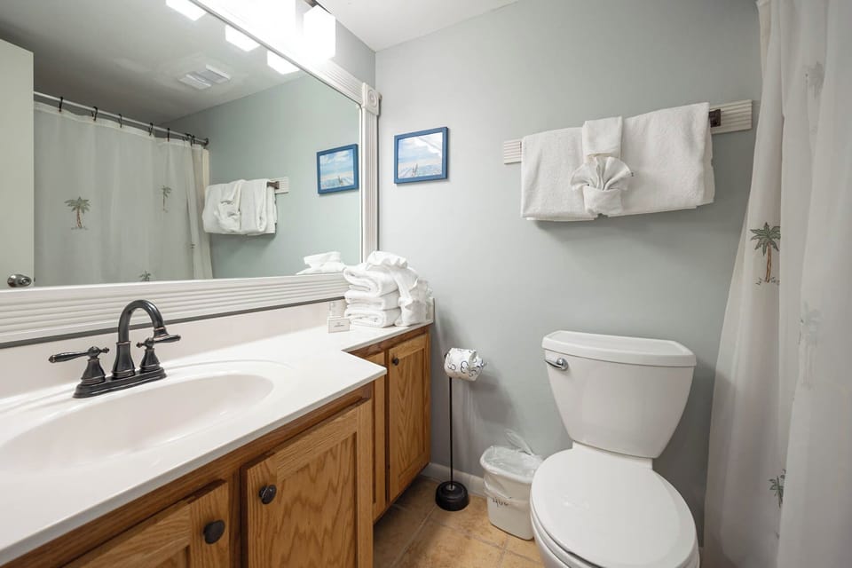 Guest bath features an oak vanity, a large mirror, and neatly stacked fluffy towels for a refreshing experience
