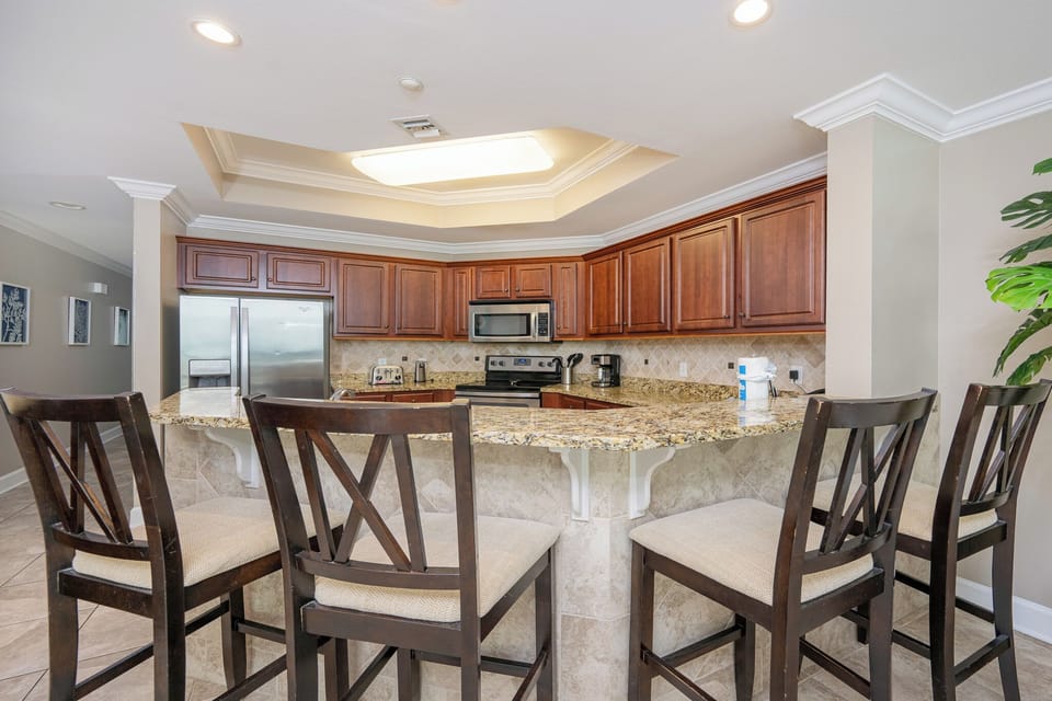 Experience a modern kitchen with rich wood cabinetry, granite countertops, and stylish bar seating for casual dining