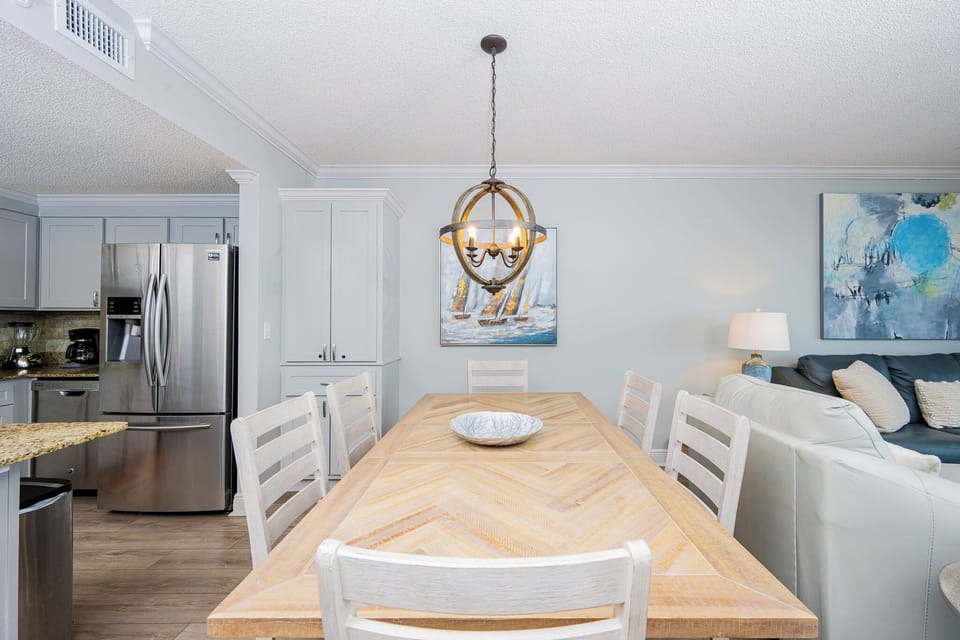 Gather around the large dining table, illuminated by a stylish chandelier, perfect for meals and conversation
