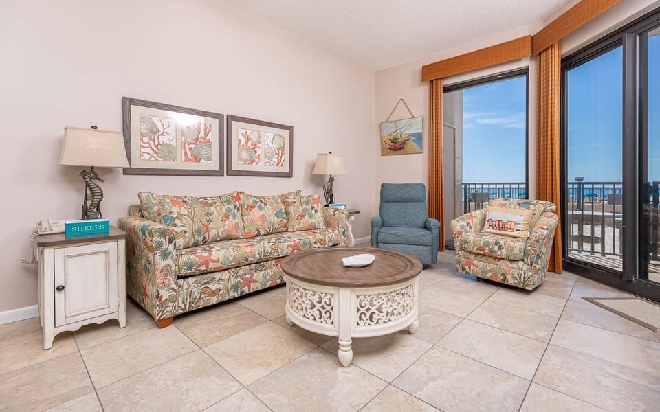 Relax in the inviting living area with a floral sofa with queen sleeper, decorative coffee table, and beachfront views