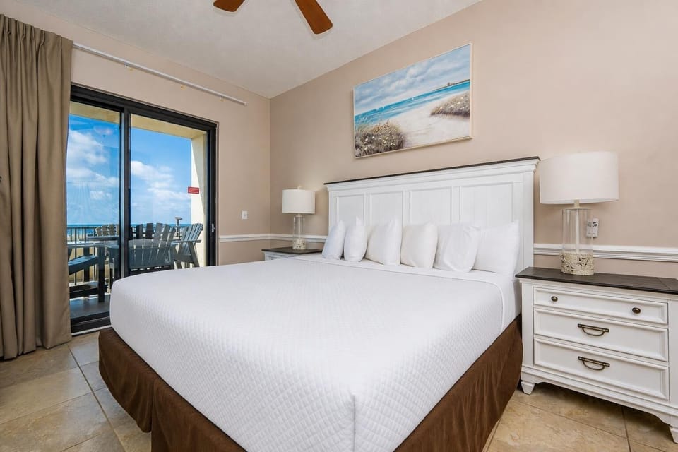 Relax in the master bedroom featuring a king bed, stylish decor, and access to a scenic beachfront balcony