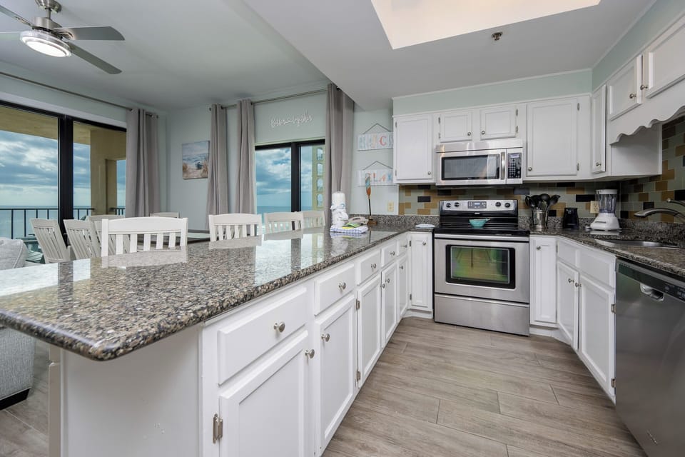 This kitchen features sleek stainless appliances, granite countertops, and a welcoming view of the beach from the dining area