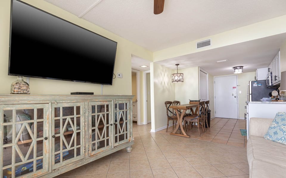 This inviting living area features a large TV, a charming cabinet, and a cozy dining space, perfect for relaxation and meals