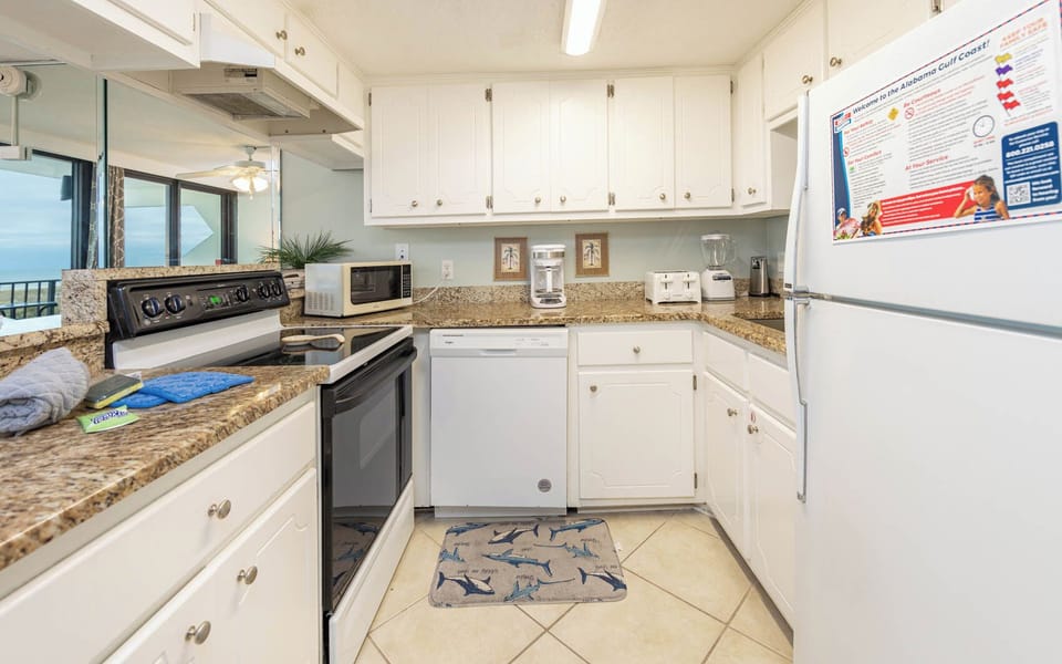 Welcoming kitchen featuring granite countertops, modern appliances, and a cozy shark-themed mat for added charm