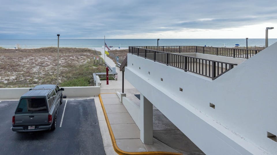 A serene view of sandy dunes and calm waters from the balcony, perfect for beachside relaxation