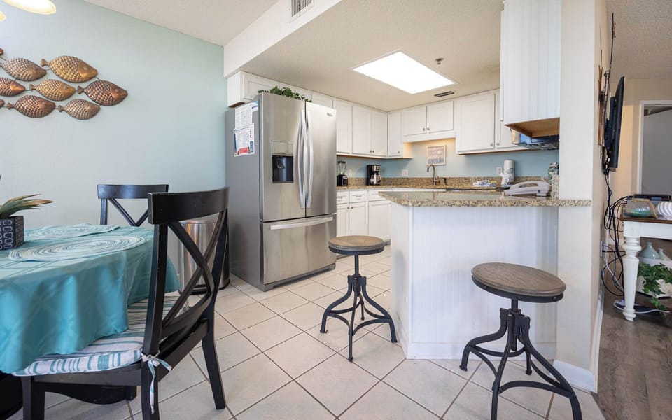 Bright kitchen area featuring a granite countertop, stainless appliances, and a cozy breakfast bar with stylish seating