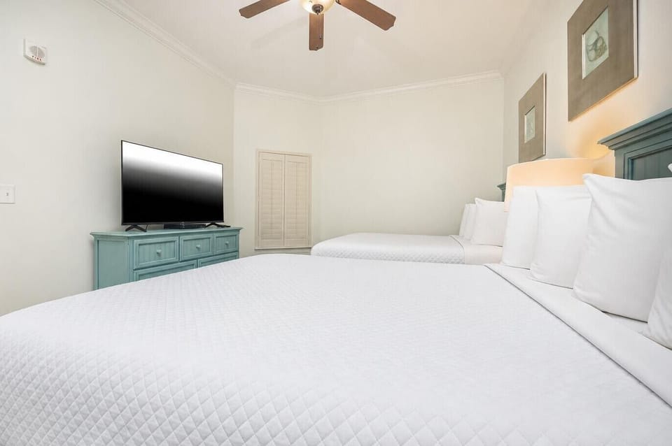 This guest bedroom features two queen beds, a TV for entertainment, and soft, neutral tones for a relaxing atmosphere