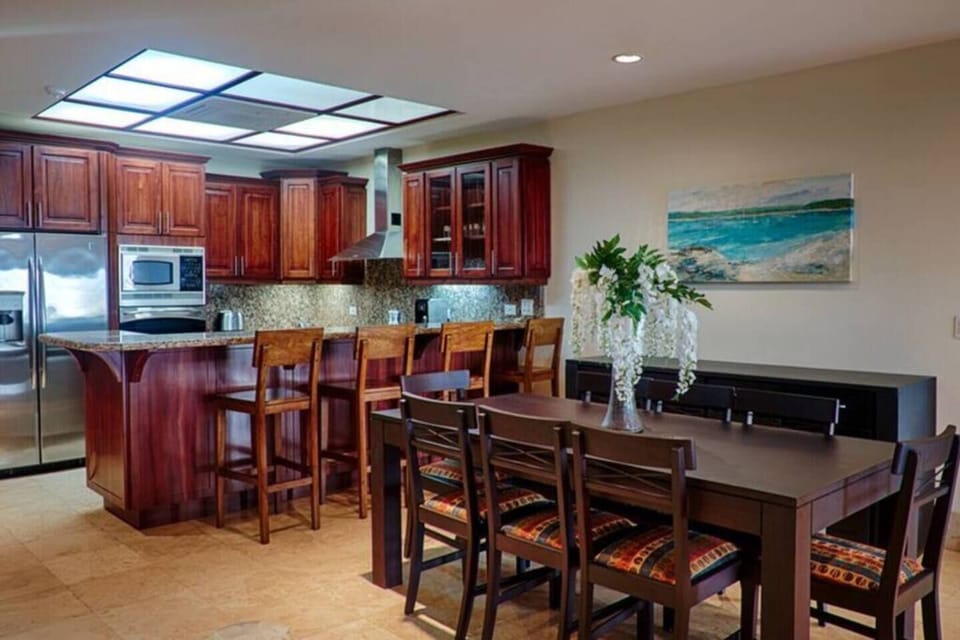 Stylish dining area with seating for six, perfect for shared meals after beach days. Features natural wood table, tropical decor, and open layout connecting to kitchen and living room. Ideal for families or groups visiting Tamarindo, Costa Rica.