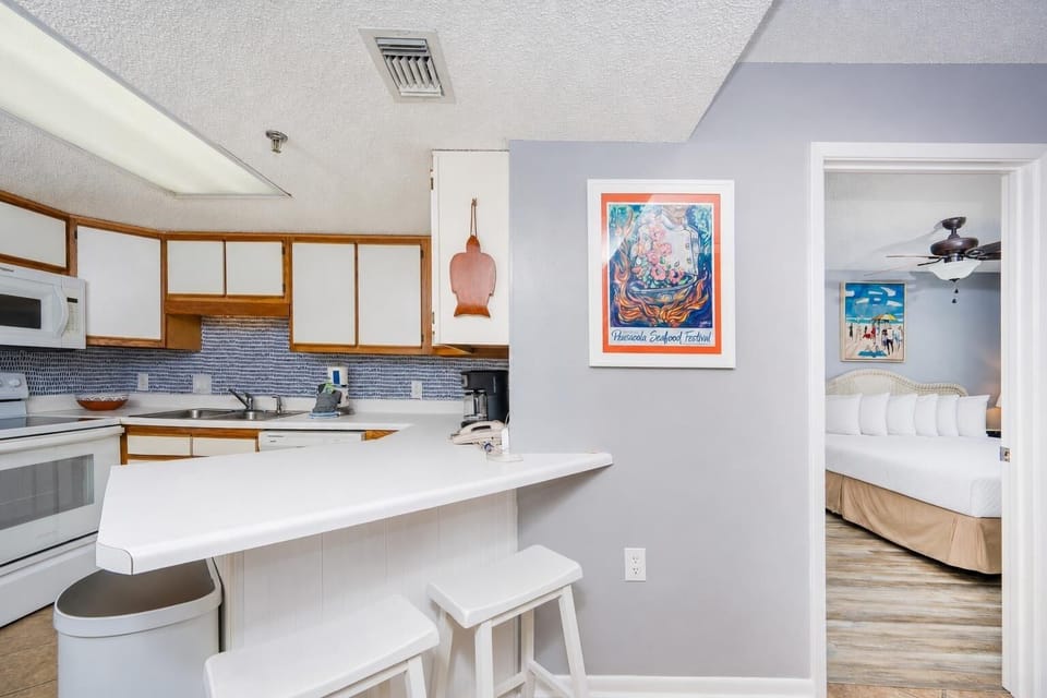 Kitchen with white cabinetry and all essential appliances, offering a view on the beach