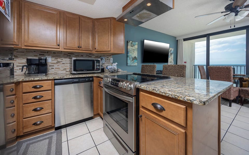 This kitchen features granite countertops, stainless appliances, and a view of the beach from the dining area