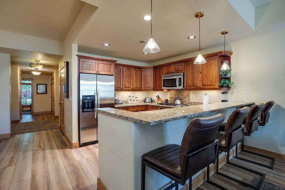 Gather around this stunning granite kitchen island with rich wood cabinets and modern appliances for memorable meals together.