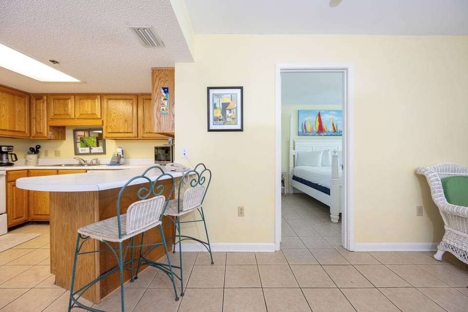 Kitchen area featuring wooden cabinetry, a breakfast bar with seating, and a view into a cozy bedroom with nautical decor