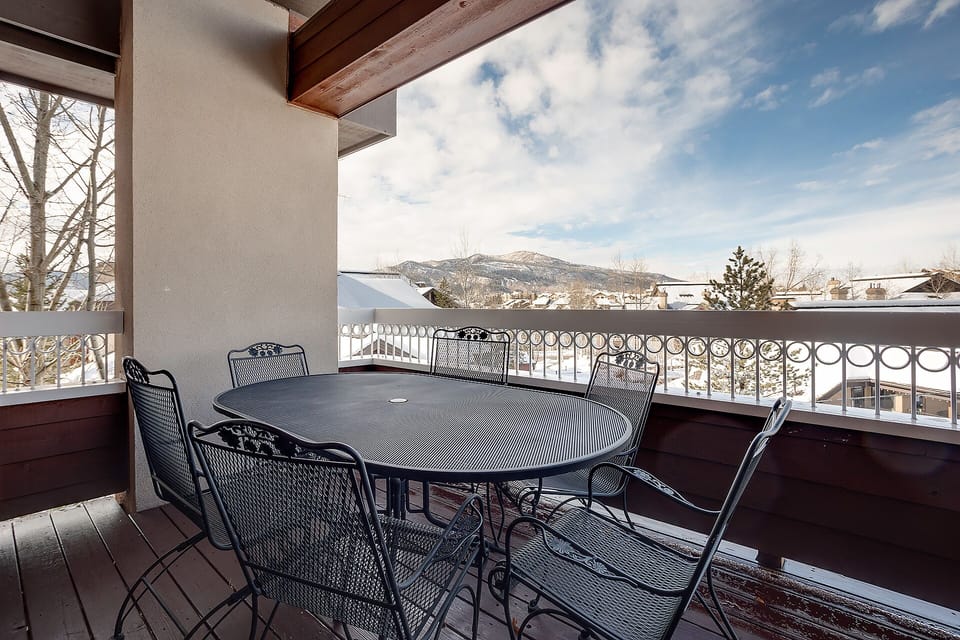 Your covered balcony offers mountain views and outdoor dining space with seating for six amid snowy winter scenery.