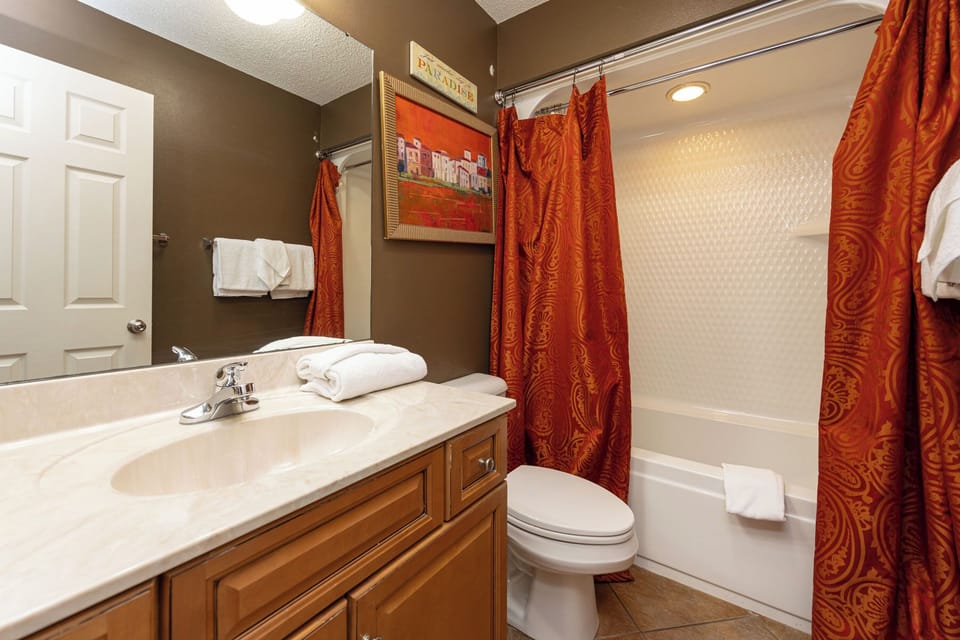 Indulge in a refreshing shower beneath soft lighting, with a touch of warmth in this guest bath
