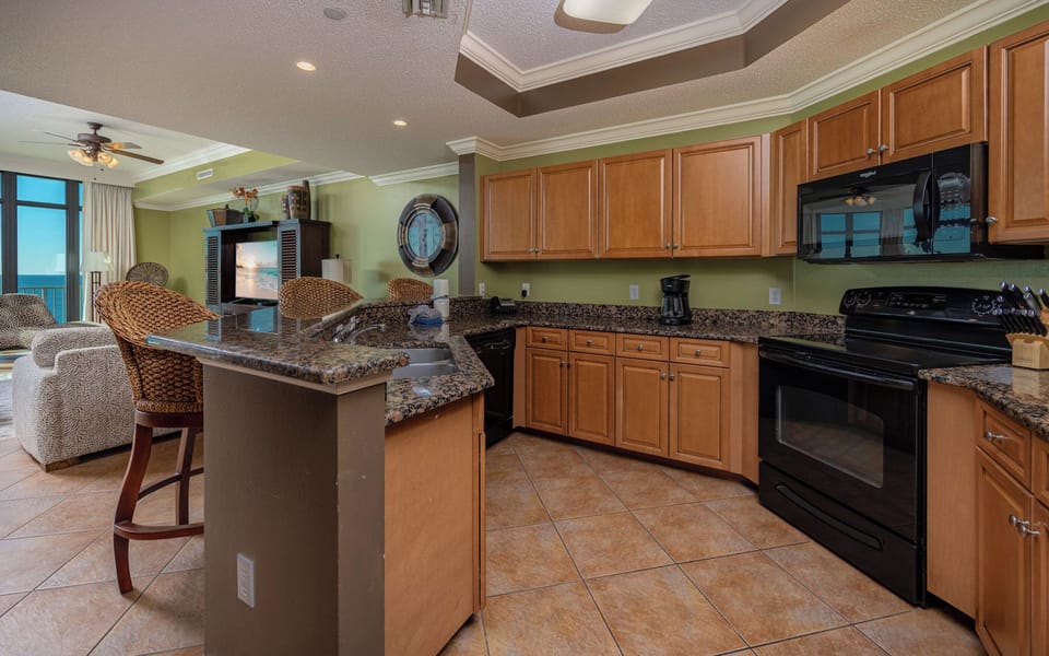 Prepare meals in this kitchen with elegant cabinetry, black appliances, and spacious countertops